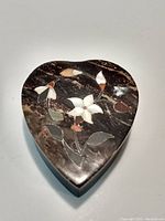 Closed heart-shaped rock trinket box with floral inlay on the lid.