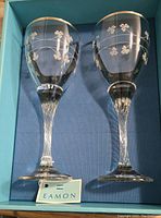 Two clear glass wine glasses with silver rims and claddagh etched decoration in original blue striped box with Eamon tag.
