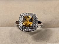 Front view of sterling silver ring with central square-cut Brazilian citrine gemstone and surrounding white zircon stones.