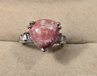 Front view of sterling silver ring with triangular pink stone center and side accents