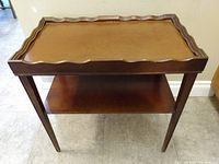 Front angle view of the vintage rectangular wooden table showing wavy trim top and lower shelf.