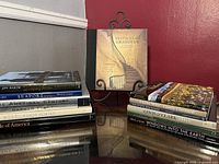 Books displayed in two stacks on a reflective surface with a red wall background, showing the decorative covers and titles.