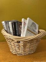 Beige wicker basket holding six hardcover books with visible spines about Princess Diana's life.