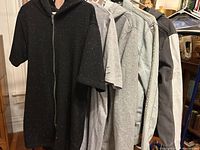 Black short sleeve zip-up hoodie with speckled design, two hoodies and denim jackets on rack