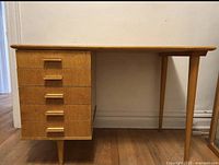 Side view of mid century ladies desk showing five drawers with wooden handles and tapered legs.