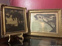 Two framed photographs side by side on table against red wall