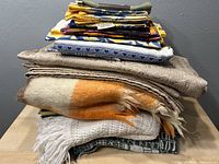 Stack of folded blankets and throws including Hudson Bay wool throw and knitted throws