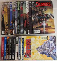 Top view of 20 comic books arranged to show cover art and spines featuring 'The Crusades' title, showcasing various cover artworks with moody and stylized illustrations related to the series.