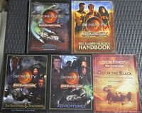 Five Serenity role playing game books on a dark woven surface, showing covers with title and character images including spacecraft and cast.