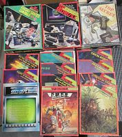 Overview of the three boxed games and eleven spy-themed booklets arranged on a surface.