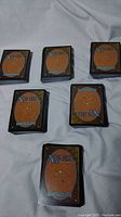 Multiple stacks of Magic the Gathering cards arranged on a surface showing the card backs.