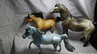 Three large Breyer horse models positioned together showcasing damage and details.