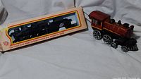 Photo showing vintage cast iron metal train engine in red and black and boxed black scale model railroad engine