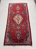 Full view of the rectangular Persian Lilian rug with red field and floral medallion design.