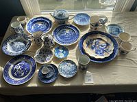Overview of all porcelain items displayed on table in natural daylight showing variety of plates, cups, and serving dishes