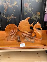 Full view of the five carved wood marine-themed decorative sculptures arranged on a wooden table.