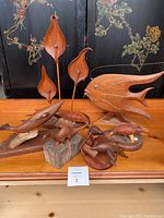 Full group of carved wood decor items: large fish, abstract leaf sculpture, smaller fish, and small animal figures on blocks.