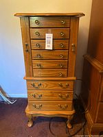 Full front view of the tall wood jewelry cabinet with drawers and side doors.