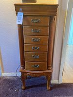 Full view of the wooden jewelry cabinet showing six drawers with vintage style metal handles and carved legs
