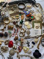 Wide shot of all jewelry pieces spread on a white surface including necklaces, bracelets, earrings, pendants, and brooches.