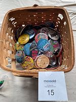 Overview of basket filled with assorted collectible buttons and pins showing multiple designs and colors.