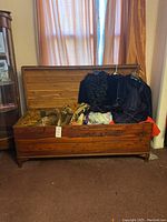 Full view of wooden blanket chest open showing contents inside