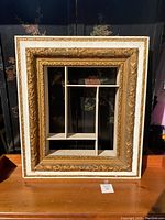 Full front view of the large vintage shadow box wall display showing ornate carvings, multiple compartments inside, and overall rectangular shape.