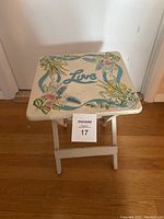 Top view close-up of the small white folding table with floral 'Love' design on the tabletop.