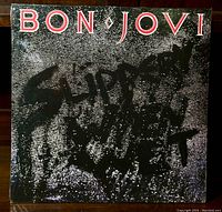 Front cover of Bon Jovi 'Slippery When Wet' vinyl LP record sealed in shrink wrap, showing album artwork and title.