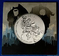Front view of 2016 silver coin depicting Batman and Superman in combat with city skyline background on original folder.
