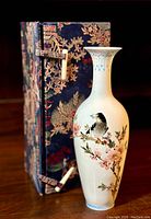 Chinese Famille Rose porcelain vase displayed next to original floral brocade box with wooden toggles