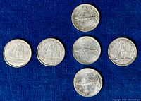 Five Canadian dimes arranged on a blue background, showing reverse side with Bluenose schooner design. Coins exhibit wear and patina from circulation.
