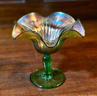 Front view of the vintage Northwood carnival glass compote showing its colorful iridescent ruffled glass bowl and green stemmed foot.