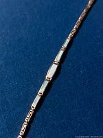 Close-up of bracelet sections showing blue mother of pearl inlaid rectangular links adjacent to silver Greek eternity key pattern links