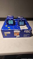 Two smaller boxes of EBC brake pads and one larger box of EBC precision brake rotors with blue packaging and yellow stars.