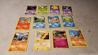Top-down image showing 12 assorted Pokemon cards arranged in three rows.