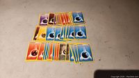 Overview of many Pokémon energy cards of different elemental types arranged in rows on a surface.