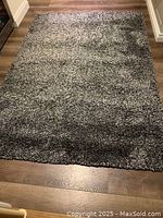 Full view of the rectangular charcoal shag rug laid on a wooden floor, showing overall size and pile texture.