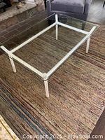 Angled top-down view showing clear glass top and white metal frame.