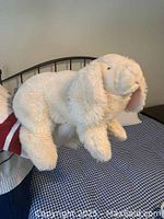 Side view of one large cream-colored plush bunny showing textured fur and floppy ears with pink lining. Hand puppet opening visible.