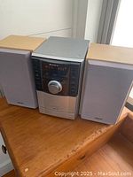 Front view of entire Sony CMT-EH10 stereo system including main unit and two speakers on wooden table.