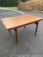 Overall view of teak dining table outdoors, leaf closed