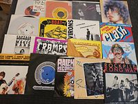 Multiple 45 singles laid out showing punk, ska, and indie bands including The Cramps, Captain Beefheart & The Magic Band, The Clash, and others.