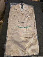 Top view of the beige ladies outfit jacket and skirt, folded and sealed in a transparent plastic cover with visible embroidery patterns.