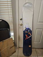 Front view of snowboard showing cartoon snowboarders on blue mountain design.