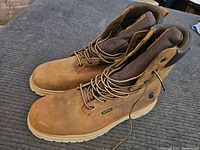 Side and top view of brown Carhartt boots showing overall condition and lace-up design.