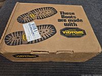 Closed brown cardboard box with Vibram logo and shoe sole tread image, showing original packaging and attached shipping label.