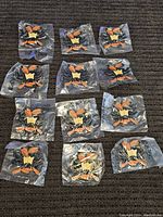 Twelve sealed Hekyl and Jekyl enamel pins laid out on a dark surface.