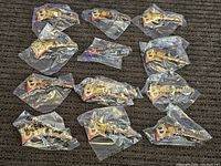 One dozen Kellogg's cereal mascot pins, all brand new and sealed in individual plastic bags, laid out on a surface.