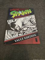 Front cover of oversized Todd McFarlane Spawn Vault Edition hardcover book showing colorful and black and white cover art with the title and Image Comics logo.